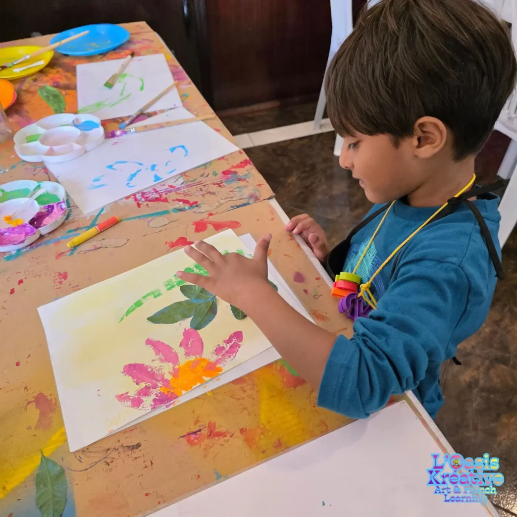 Enfant réalisant un tableau en impressions végétales avec des feuilles naturelles et de la peinture lors d’un atelier créatif animé par Zazie Jam à L’Oasis Kréative – Art & French Learning à Curepipe.