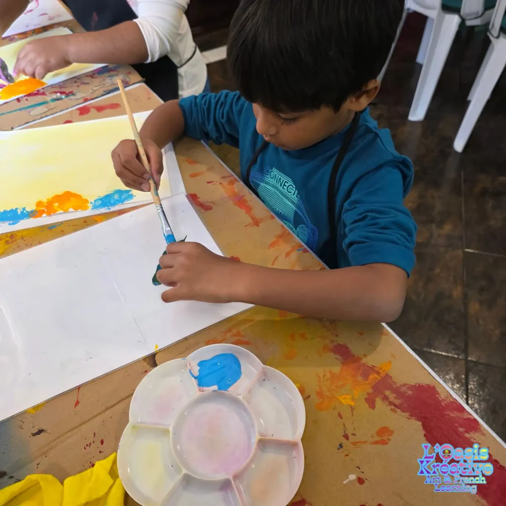 Jeune enfant peignant une feuille pour réaliser un tableau en impressions végétales lors d’un atelier créatif animé par Zazie Jam à L’Oasis Kréative – Art & French Learning à Curepipe.