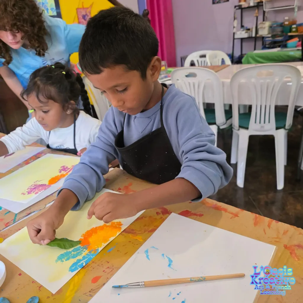 Enfants réalisant des tableaux en impressions végétales avec des feuilles et de la peinture lors d’un atelier créatif animé par Zazie Jam à L’Oasis Kréative – Art & French Learning à Curepipe.