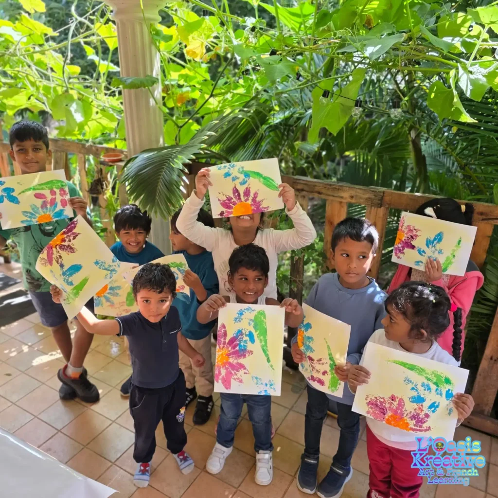 Enfants fiers de présenter leurs tableaux en impressions végétales colorées lors d'un atelier créatif avec Zazie Jam à L'Oasis Kréative à Curepipe.