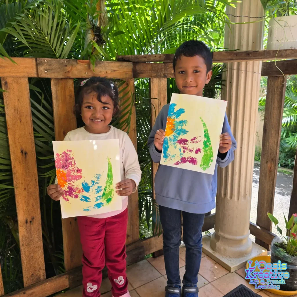 Deux enfants tiennent leurs tableaux réalisés en impressions végétales lors d’un atelier avec Zazie Jam à l’Oasis Kréative à Curepipe.