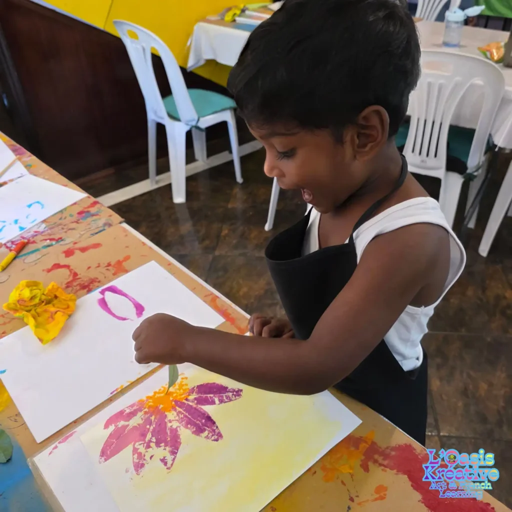 Enfant réalisant un tableau en impressions végétales avec des feuilles et de la peinture lors d’un atelier créatif animé par Zazie Jam à L’Oasis Kréative – Art & French Learning à Curepipe.
