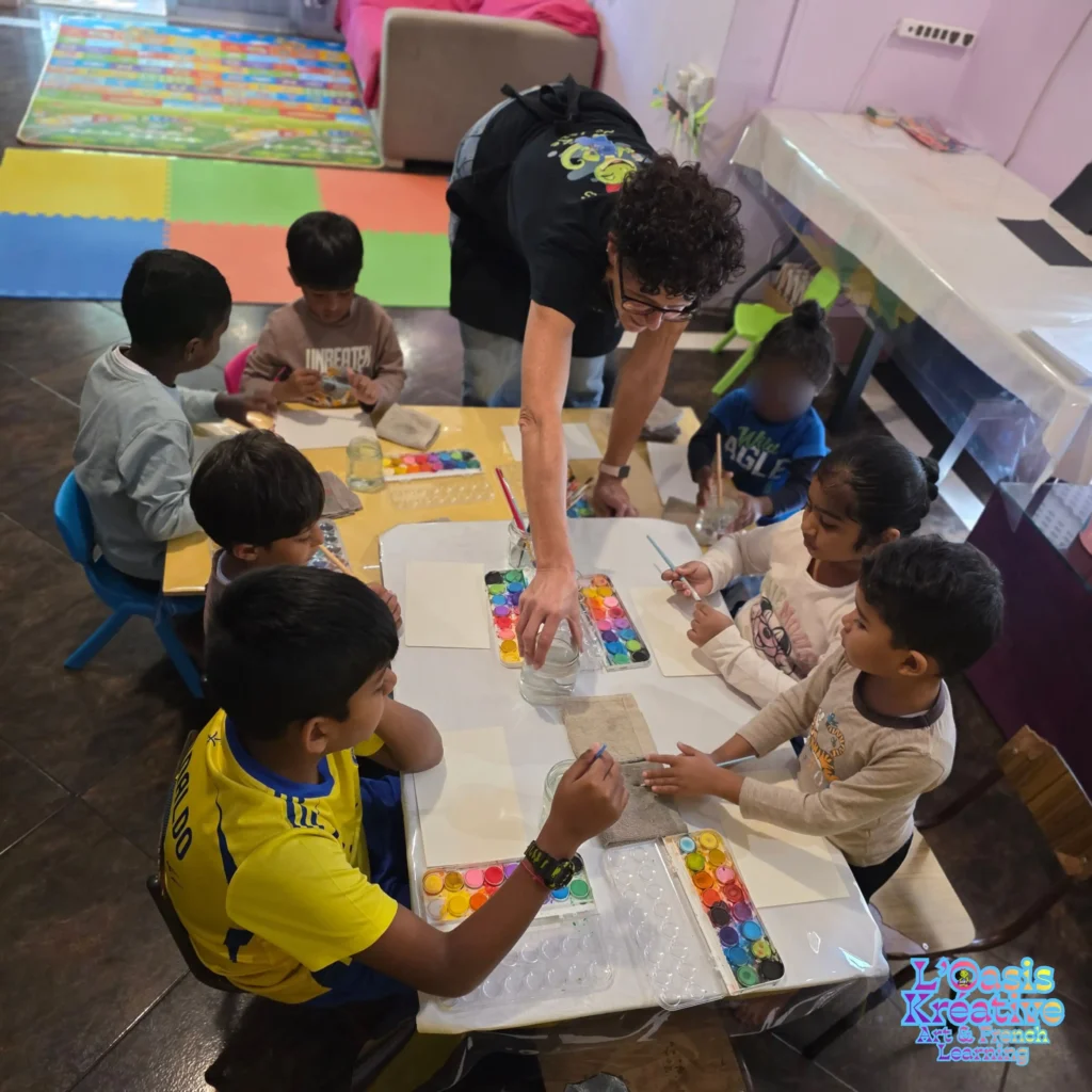 Zazie guide un groupe d'enfants autour d'une table de peinture aquarelle lors d'un atelier artistique du Samedi Rékreatif à L'Oasis Kréative, Curepipe, Maurice.